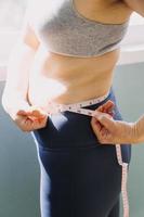 Beautiful fat woman with tape measure She uses her hand to squeeze the excess fat that is isolated on a white background. She wants to lose weight, the concept of surgery and break down fat under the photo