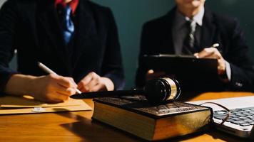 Business and lawyers discussing contract papers with brass scale on desk in office. Law, legal services, advice, justice and law concept picture with film grain effect photo