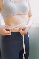 Beautiful fat woman with tape measure She uses her hand to squeeze the excess fat that is isolated on a white background. She wants to lose weight, the concept of surgery and break down fat under the photo