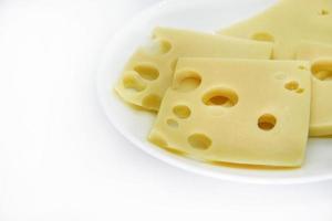 Pieces of cheese with holes on a white plate. Slices of cheese with big holes. Delicious cheese on a plate. photo