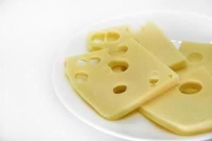 Pieces of cheese with holes on a white plate. Slices of cheese with big holes. Delicious cheese on a plate. photo