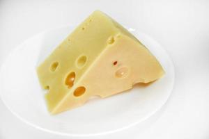 A large piece of cheese on a white background. A triangular piece of cheese with holes. photo