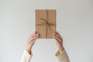 manos de mujer sosteniendo la caja de regalo con un lazo de cinta. concepto minimalista de dar un regalo. foto