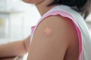 Vaccinated little asian girl with adhesive plaster after vaccine injection photo