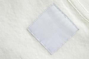 Blank white laundry care clothes label on fabric texture background photo