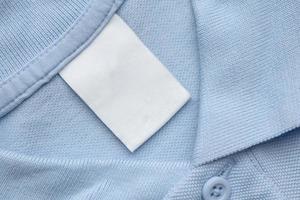 etiqueta de ropa blanca en blanco para el cuidado de la ropa sobre fondo de tela de camisa azul foto