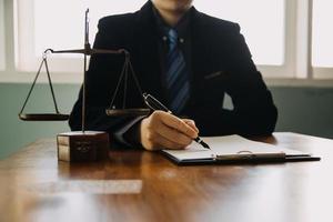 Business and lawyers discussing contract papers with brass scale on desk in office. Law, legal services, advice, justice and law concept picture with film grain effect photo