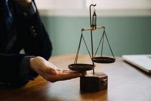 Business and lawyers discussing contract papers with brass scale on desk in office. Law, legal services, advice, justice and law concept picture with film grain effect photo