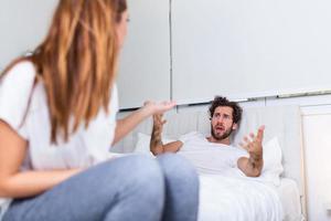 Couple With Problems Having Disagreement In Bed. Frustrated couple arguing and having marriage problems, Young couple into an argument on bed in bedroom photo