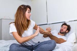 Couple With Problems Having Disagreement In Bed. Frustrated couple arguing and having marriage problems, Young couple into an argument on bed in bedroom photo