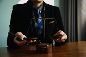 Business and lawyers discussing contract papers with brass scale on desk in office. Law, legal services, advice, justice and law concept picture with film grain effect photo