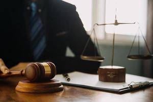 Business and lawyers discussing contract papers with brass scale on desk in office. Law, legal services, advice, justice and law concept picture with film grain effect photo