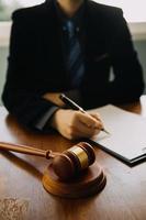 Business and lawyers discussing contract papers with brass scale on desk in office. Law, legal services, advice, justice and law concept picture with film grain effect photo