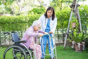 médico ayuda y cuidado paciente asiático mayor o anciano mujer sentada en silla de ruedas en el parque en la sala del hospital de enfermería, concepto médico fuerte y saludable. foto