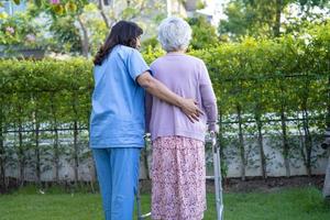 Doctor help and care Asian senior or elderly old lady woman use walker with strong health while walking at park in happy fresh holiday. photo