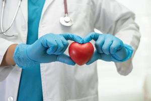 médico sosteniendo un corazón rojo en la sala del hospital, concepto médico fuerte y saludable. foto