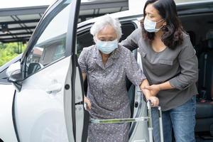 Caregiver help and support asian senior or elderly old lady woman patient walk with walker prepare get to her car, healthy strong medical concept. photo