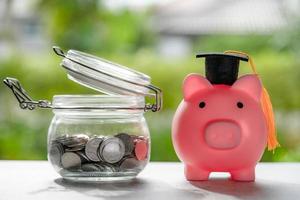 Save money coins in grass jar with piggy bank and graduation cap, Business finance education concept. photo