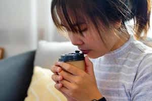 Asian woman enjoying coffee at home, the concept of resting after work, relaxing, cozy corner, peaceful corner. Soft and selective focus. photo