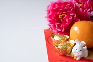 Chinese New Year of the rabbit festival concept. Orange, red envelopes, two rabbits and gold ingot decorated with plum blossom on white background. photo