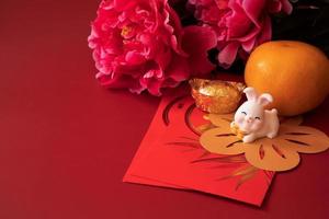 Chinese New Year of the rabbit festival concept. Mandarin orange, red envelopes, rabbit and gold ingot decorated with plum blossom on red background. photo