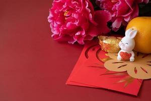 Chinese New Year of the rabbit festival concept. Mandarin orange, red envelopes, rabbit and gold ingot decorated with plum blossom on red background. photo