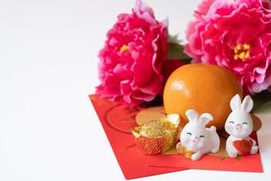 Chinese New Year of the rabbit festival concept. Orange, red envelopes, two rabbits and gold ingot decorated with plum blossom on white background. photo