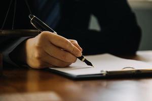 Business and lawyers discussing contract papers with brass scale on desk in office. Law, legal services, advice, justice and law concept picture with film grain effect photo