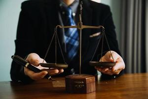 Business and lawyers discussing contract papers with brass scale on desk in office. Law, legal services, advice, justice and law concept picture with film grain effect photo
