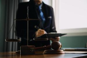 Business and lawyers discussing contract papers with brass scale on desk in office. Law, legal services, advice, justice and law concept picture with film grain effect photo