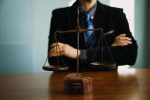 Business and lawyers discussing contract papers with brass scale on desk in office. Law, legal services, advice, justice and law concept picture with film grain effect photo