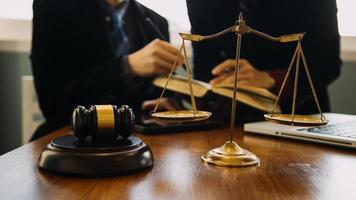 Business and lawyers discussing contract papers with brass scale on desk in office. Law, legal services, advice, justice and law concept picture with film grain effect photo