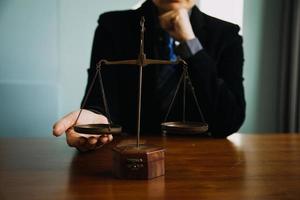 Business and lawyers discussing contract papers with brass scale on desk in office. Law, legal services, advice, justice and law concept picture with film grain effect photo