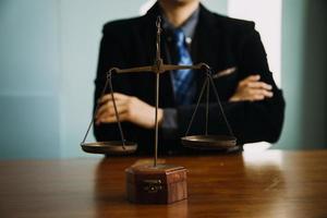 Business and lawyers discussing contract papers with brass scale on desk in office. Law, legal services, advice, justice and law concept picture with film grain effect photo