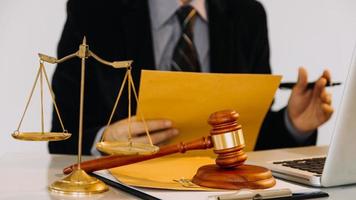 Business and lawyers discussing contract papers with brass scale on desk in office. Law, legal services, advice, justice and law concept photo