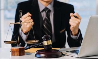 Business and lawyers discussing contract papers with brass scale on desk in office. Law, legal services, advice, justice and law concept photo