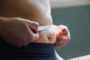 hermosa mujer gorda con cinta métrica usa su mano para exprimir el exceso de grasa que está aislado en un fondo blanco. ella quiere perder peso, el concepto de cirugía y descomponer grasa bajo el foto