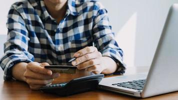 manos sosteniendo la tarjeta de crédito y usando la computadora portátil. las compras en línea foto