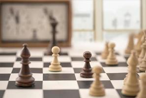 chess board with clock and figures in front of a blurry window photo