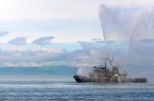 Floating tug boat is spraying jets of water photo