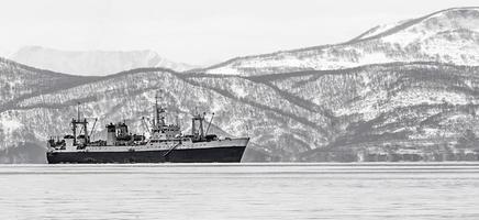 large fishing vessel on the background of snow-covered hills and volcanoes photo