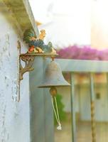 pequeña campana de hierro con gallo de colores fuera de la casa. foto