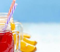 close up two cups with orange juice and strawberries on blue background photo