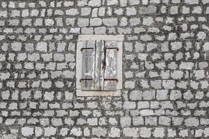 old house stone wall, with cracked window shutters in light wood photo