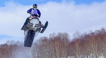 moto de nieve en salto de altura por encima de la pista. enfoque selectivo foto