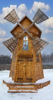 wooden windmill in winter on a background of blue sky with clouds photo