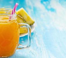 jugo de piña o batidos en una taza con un bolígrafo sobre una mesa de madera azul foto