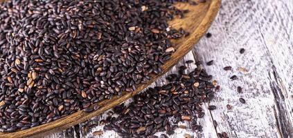 Black rice on old wooden table. Selective focus photo