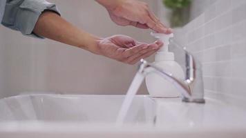 l'homme presse la bouteille de savon et les bulles de savon sur sa main en vue de se laver les mains. les hommes se lavent les mains au savon pour tuer les germes. le concept de propreté pour une bonne santé et protéger les virus. video