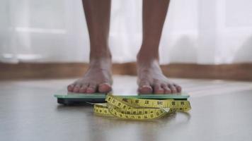 Frauenfuß treten auf Waagen mit Maßband. Eine Frau wiegt sich nach dem Essen. frau ernst über gewicht, weil sie ernährung brauchen. diätkonzept und gewichtsverlust.